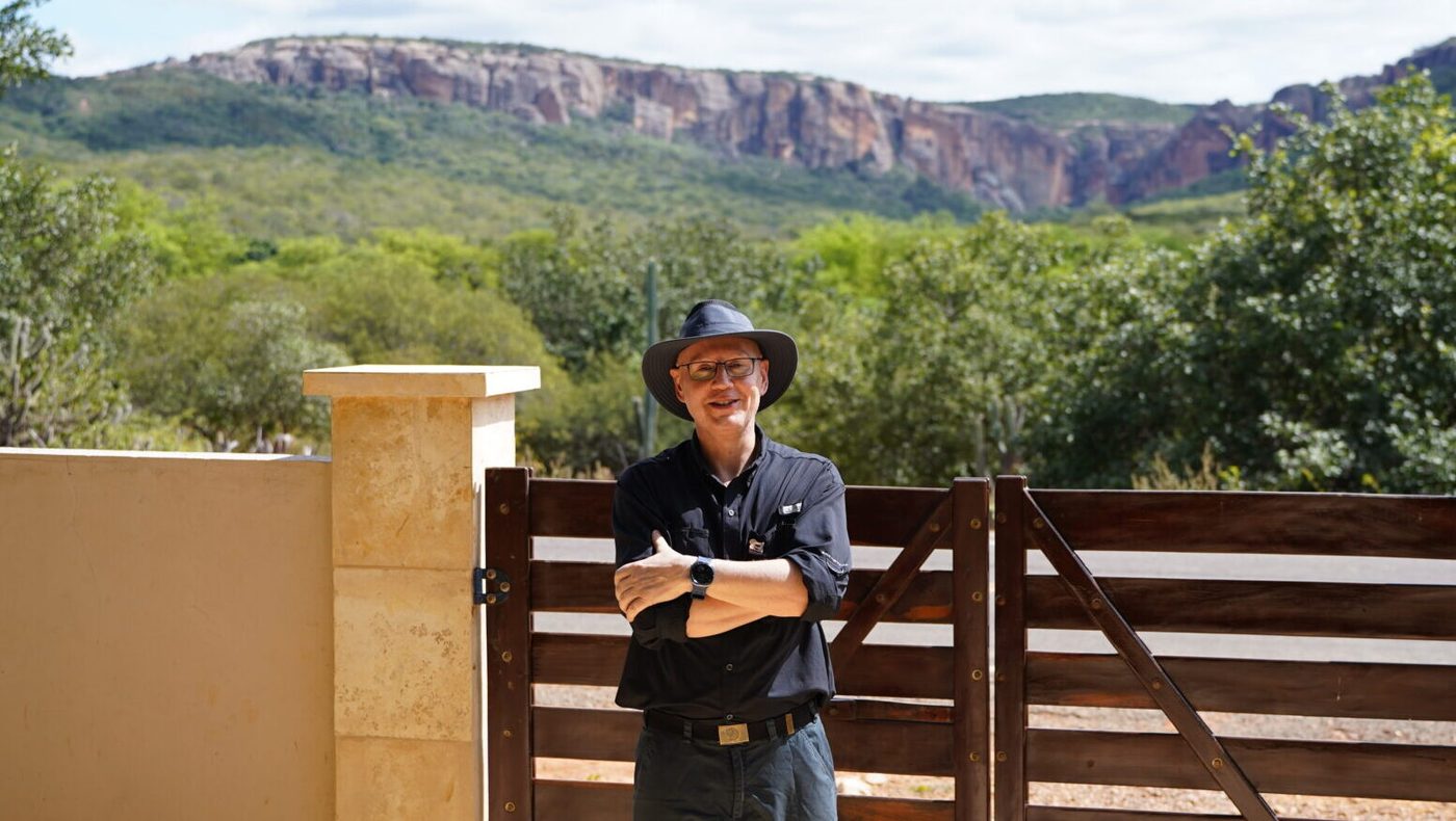 Uwe em frente ao portão, com a Serra ao fundo